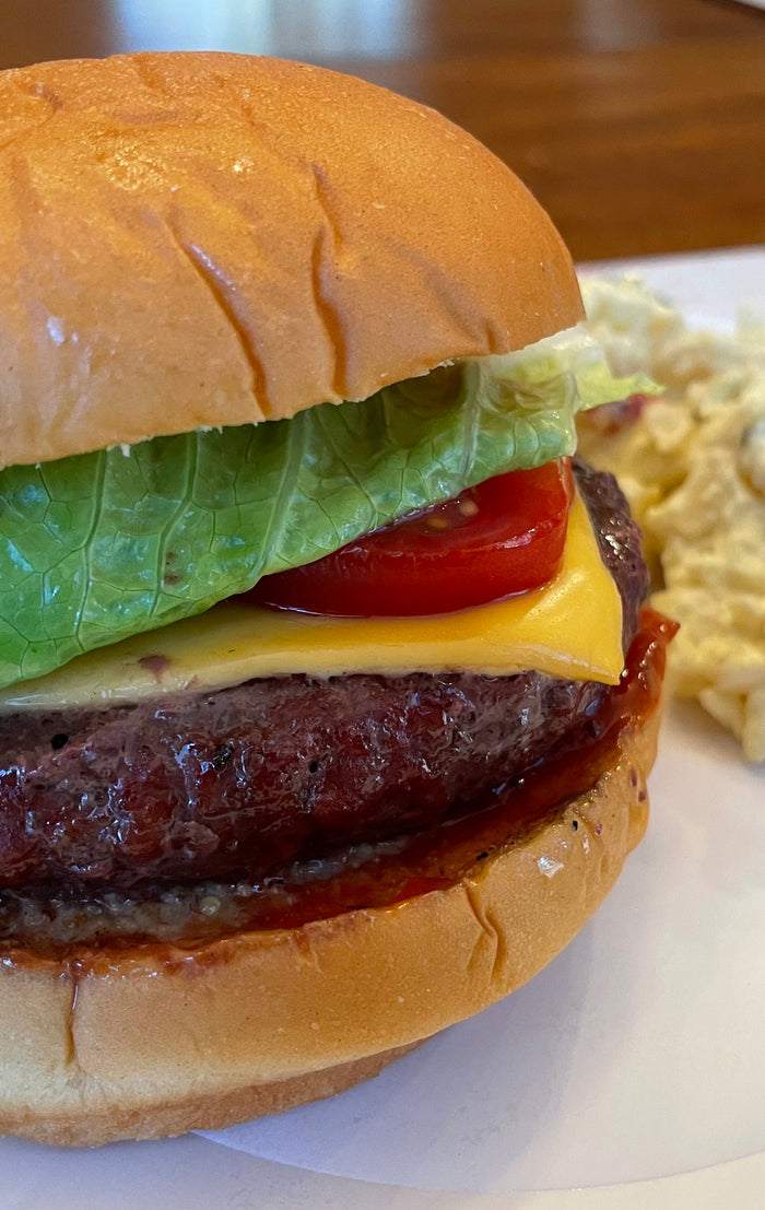 grilled hamburger on bun with lettuce, tomato and cheese.